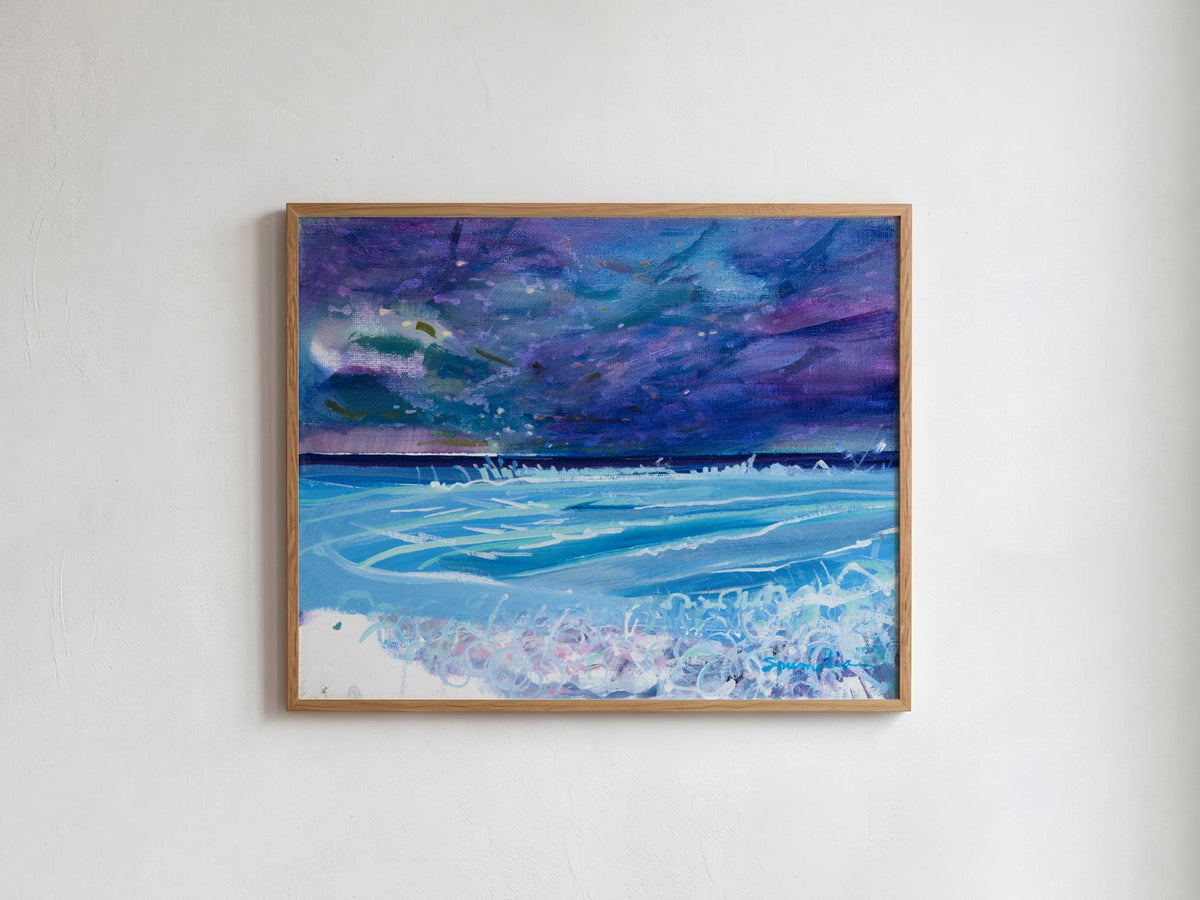 A framed painting of a stormy night sky over a blue ocean with white waves, hanging on a white textured wall.