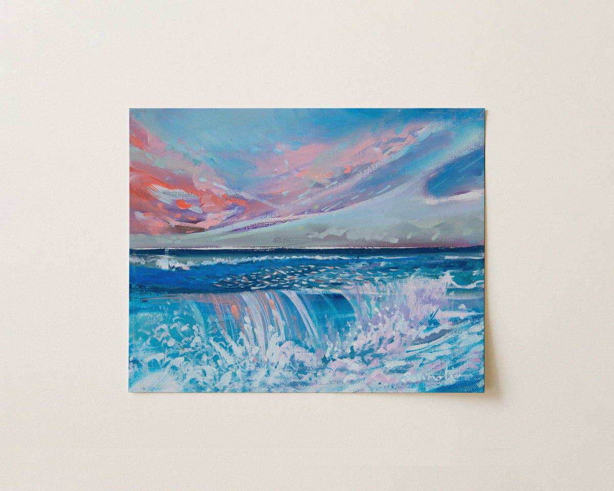 An impressionistic painting of a dramatic ocean wave under a colorful pink, blue, and white sky, displayed on a light beige wall.